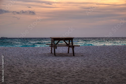 This unique photo shows a table with a bench on a beach of the Maldives during a romantic sunset © Jonny Belvedere