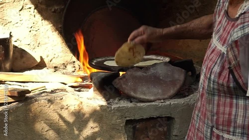 Mexican woman from Cuetzalan making authentic tortillas by hand in a typical “Comal” pan. photo