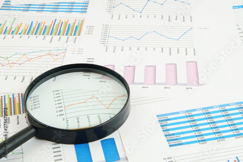 Business concept, magnifying glass on financial charts and graphs
