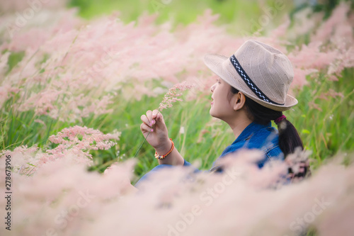 Happy young asian woman sitting on grass field