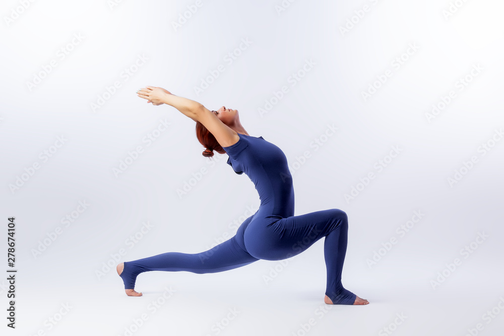 Beautiful slim woman in sports overalls  doing yoga, standing in an asana pose - Crescent on white  isolated background. The concept of sports and meditation. Training for stretching and yoga