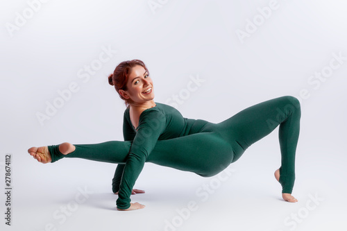  woman in sports overalls  doing yoga, standing in an asana balancing pose - posture connection  on white  isolated background. The concept of sports and meditation. Training for stretching and yoga