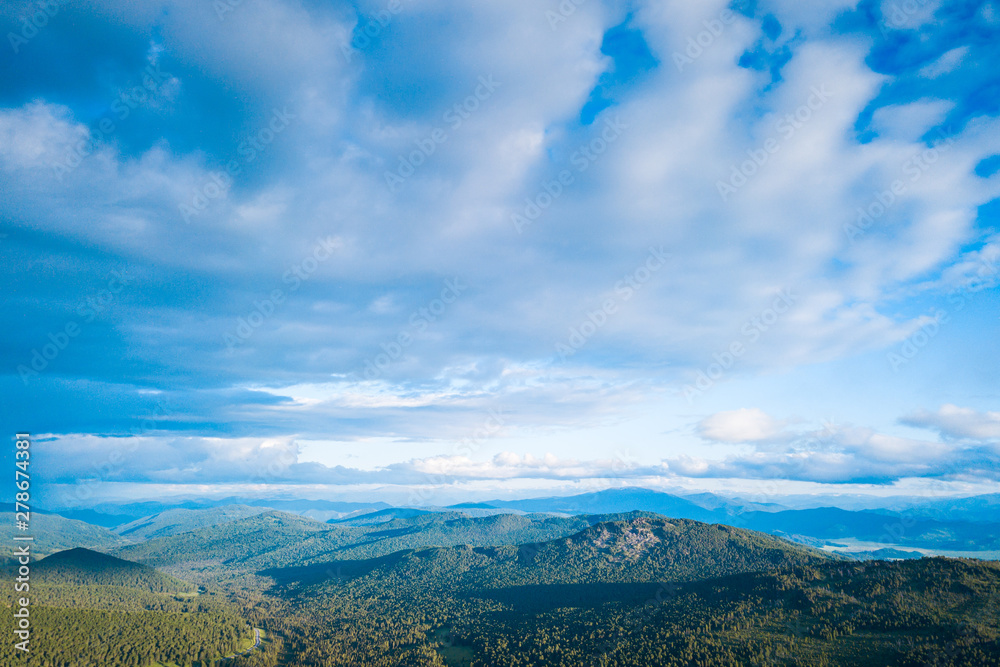 Ultra wide panorama of skyline. Green mountains covered with forest on the blue sky background.  Amazing view on green mountains from a viewpoint