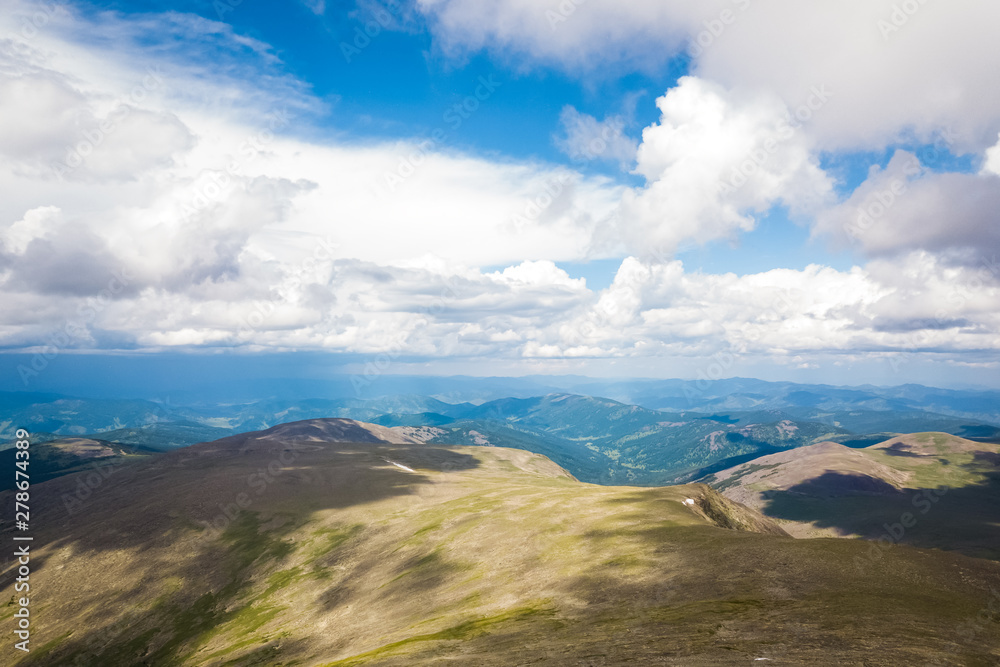 Amazing view on green mountains from a viewpoint. Panorama of the mountains in Altai on a summer clear day. A landscape view of beautiful fresh green field and Altai mountain background. Amazing view on green mountains from a viewpoint. Panorama of the mountains in Altai on a summer clear day. A landscape view of beautiful fresh green field and Altai mountain background.