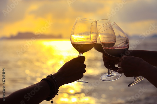 Fotografija Close up on hands holding red wine glass on balcony during sunset, celebration c