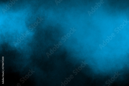 Throwing blue powder out of hand against black background. Stopping the movement of blue holi on the air use for abstract background.