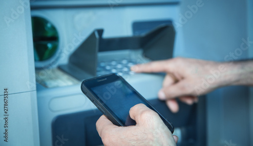 Man holding smartphone. ATM. Online transaction. Banking