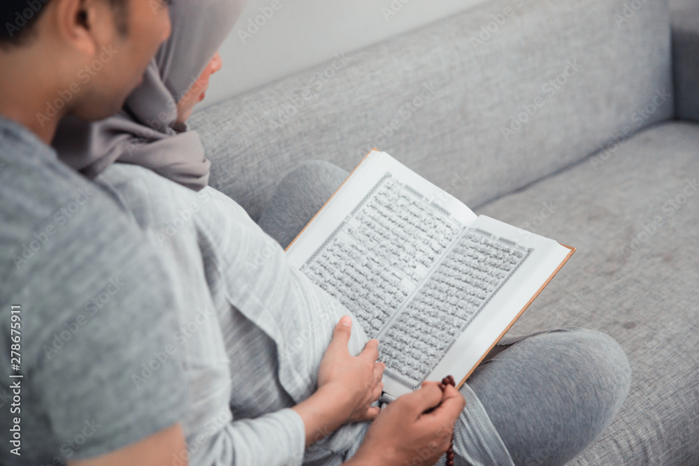 wife and husband learn how to read qoran. muslim family reading holy book of islam wife and husband learn how to read qoran. muslim family reading holy book of islam