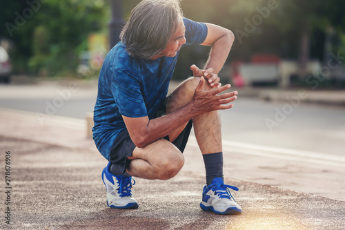 Fototapeta Naklejka Na Ścianę i Meble -  Senior man with sports running knee injury. Hands holding knee with painful.
