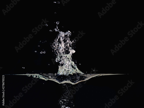 Water explosion on liquid surface isolated on black background, close up view. Waving surface, water bubbles, splash, abstract black background for overlays design, screen blending mode layer