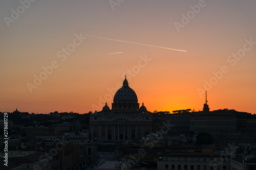 Dark silhouette of the St Peters Basilica against bright red sunset sky