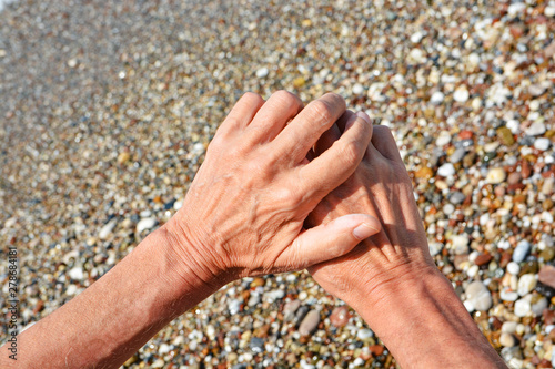 Men's tanned hands, make different compositions of fingers on the background of sea pebbles