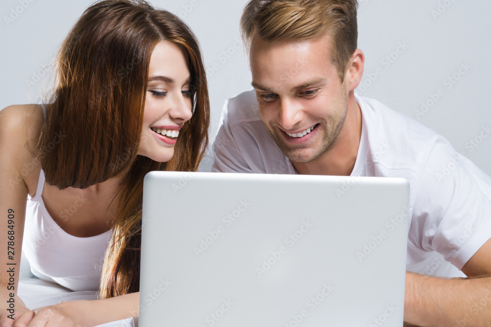 Couple using laptop, on bed Couple using laptop, on bed