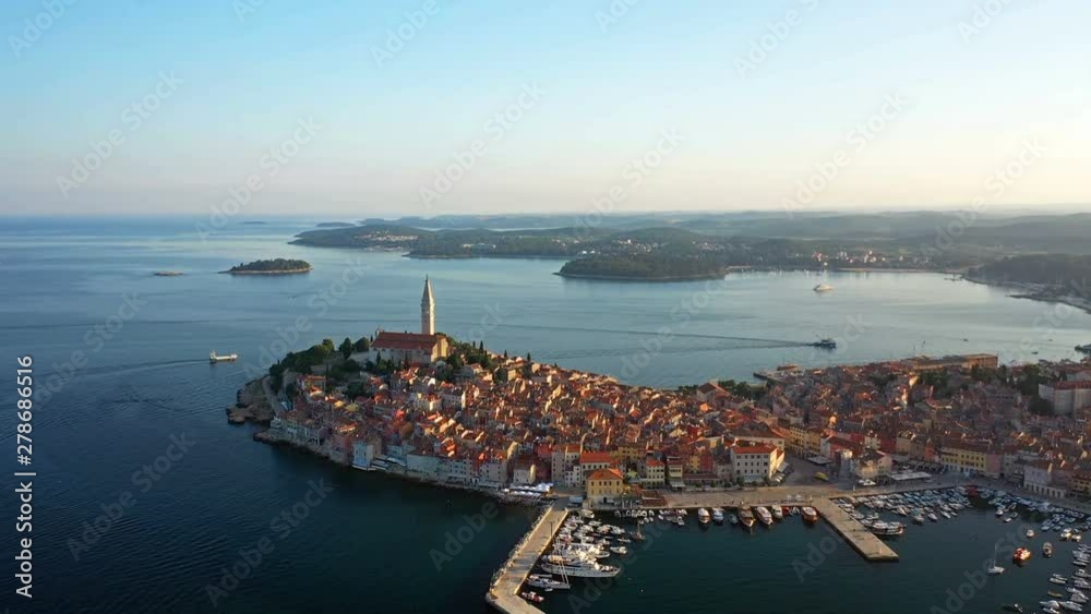 4K. Flight over beautiful Rovinj at sunrise. Morning aerial panoramic view of the old town of Rovinj, marina, church of St. Euphemia and islands. Istria, Croatia.