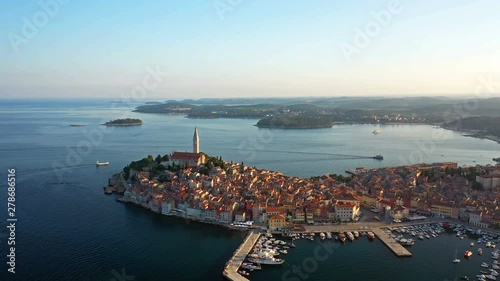 4K. Flight over beautiful Rovinj at sunrise. Morning aerial panoramic view of the old town of Rovinj, marina, church of St. Euphemia and islands. Istria, Croatia.