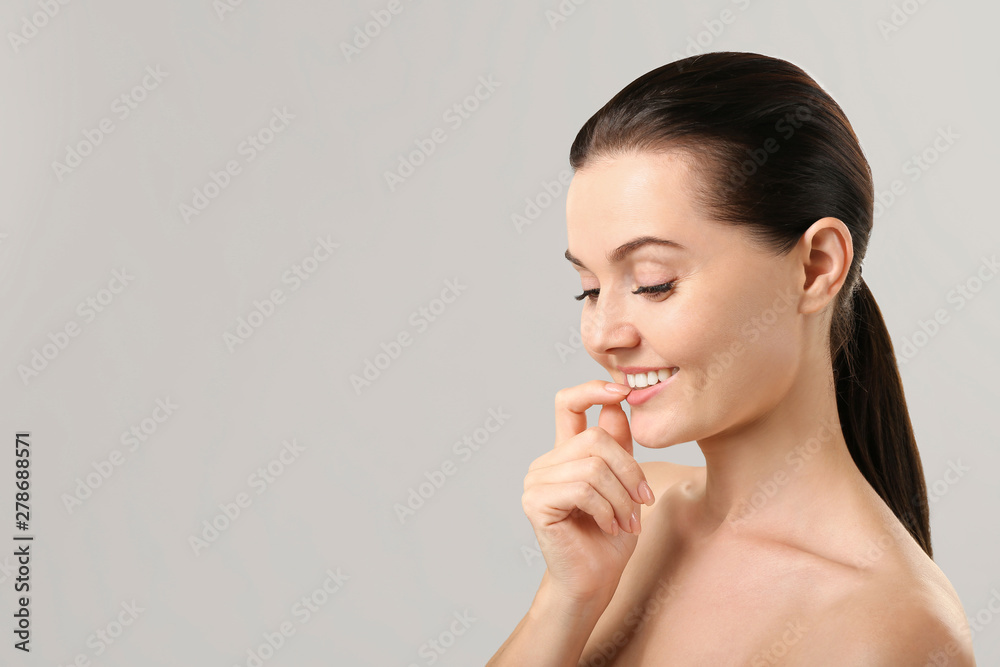 Beautiful young woman with eyelash extensions on grey background Beautiful young woman with eyelash extensions on grey background