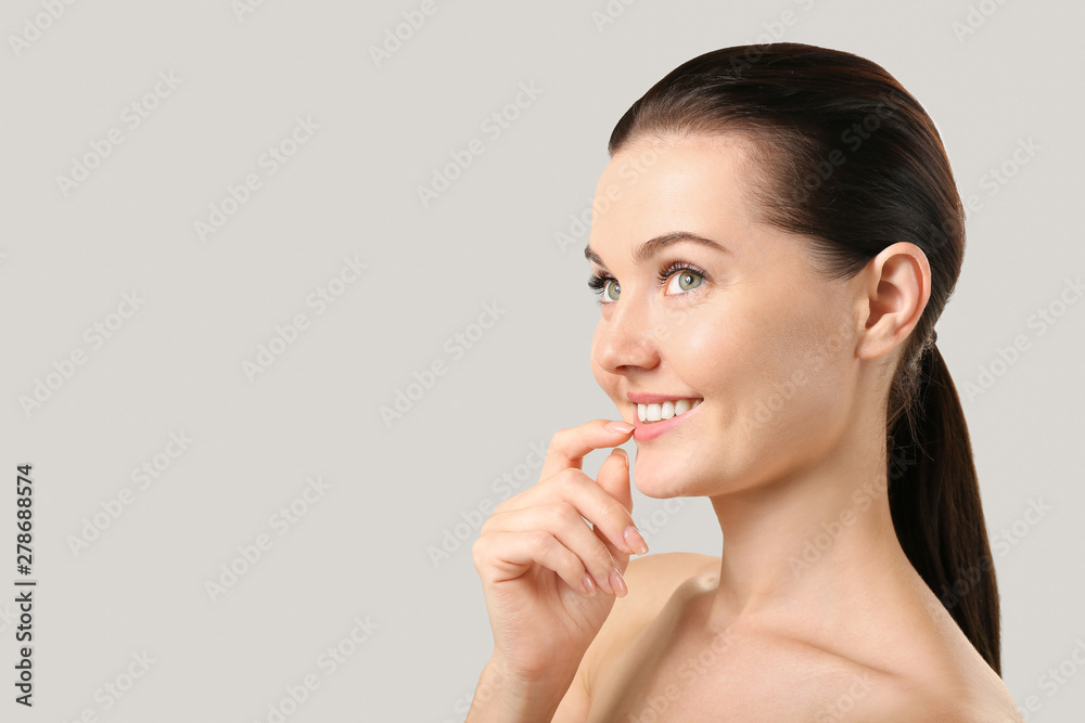 Beautiful young woman with eyelash extensions on grey background Beautiful young woman with eyelash extensions on grey background