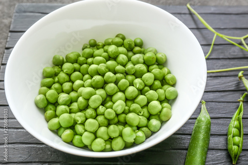 Bowl with tasty fresh peas on wooden table