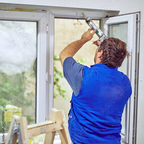 Worker using silicone for walls and widnows inside the house - r