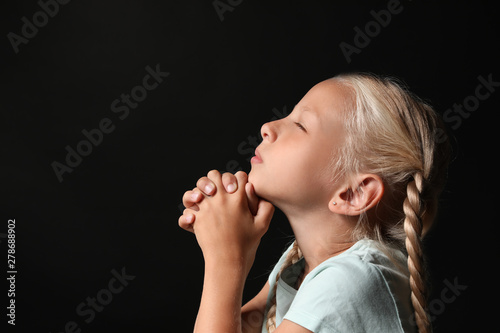 Little girl praying on dark...