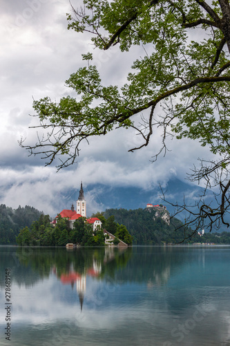 Bled, Slovenia - Misty morning view of Lake Bled (Blejsko Jezero) with the Pilgrimage Church of the Assumption of Maria and Bled Castle and Julian Alps at background on a foggy summer morning