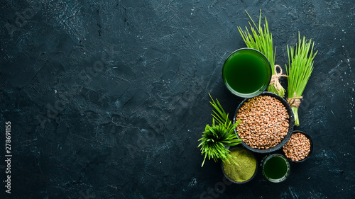 The juice from the green sprouted wheat, and wheat grains. On a black background. Micro Green. Healthy food. Top view. Free space for your text. photo