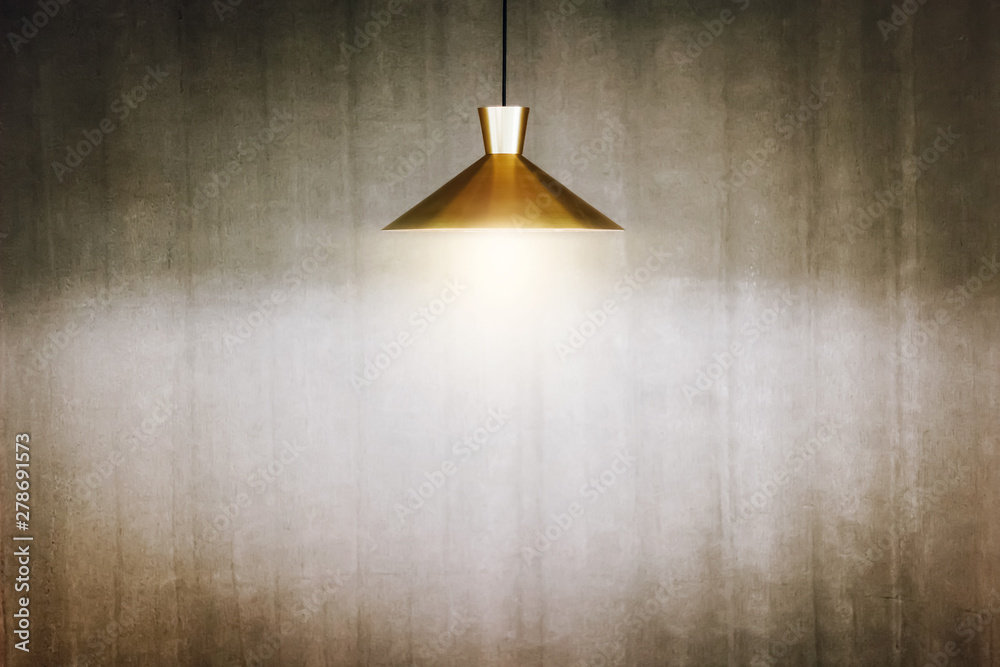 The golden lamp hang on the ceiling is shining with old concrete wall background The golden lamp hang on the ceiling is shining with old concrete wall background