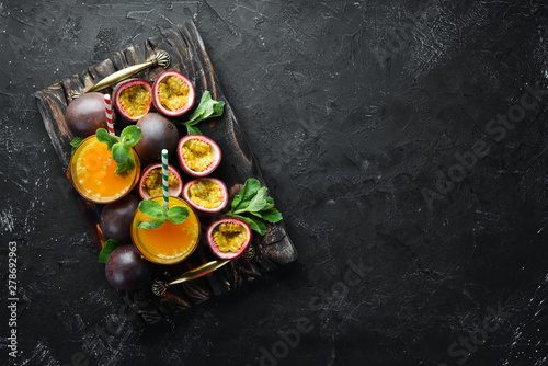 Passion fruits juice and fruit on a black background. Tropical Fruits. Top view. Free space for text. © Yaruniv-Studio