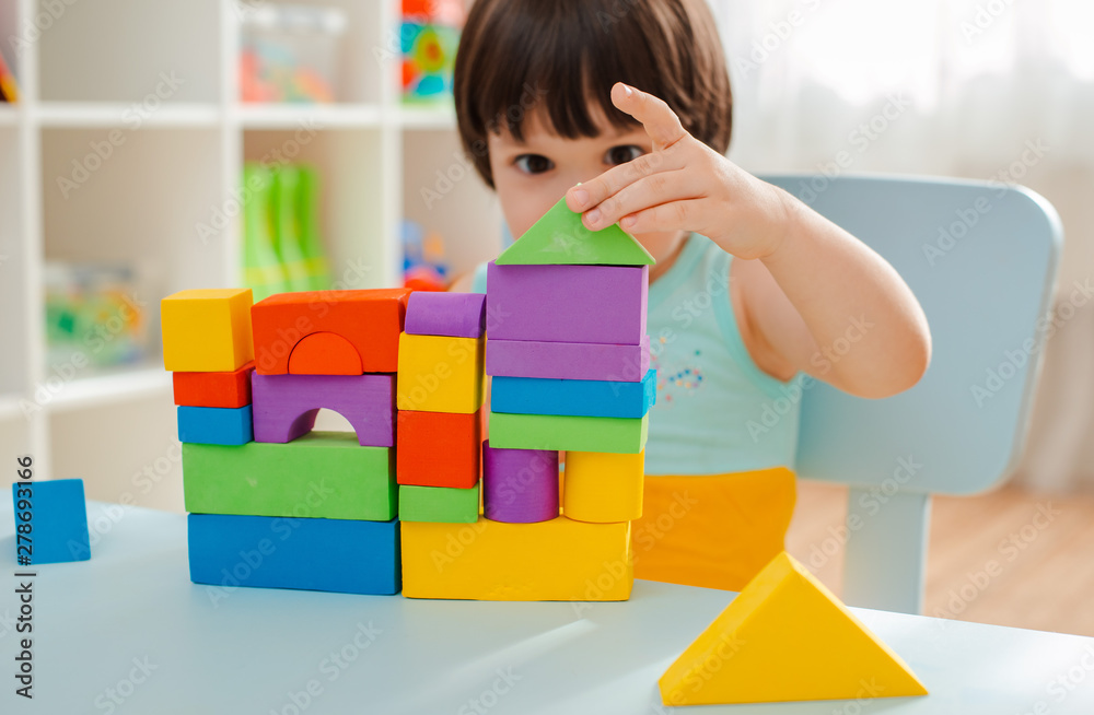 little girl collects a wooden unpainted pyramid. Safe natural wooden children's toys. little girl collects a wooden unpainted pyramid. Safe natural wooden children's toys.