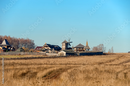 Autumn landscape. The road through the field to the entrance gate and the wooden wall of the Slavic Kremlin