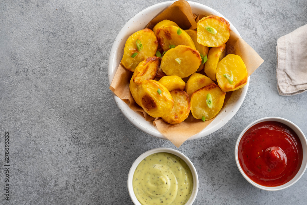 Baked potato wedges with cheese and herbs and tomato sauce on grey background - homemade organic vegetable vegan vegetarian potato wedges snack food meal. Baked potato wedges with cheese and herbs and tomato sauce on grey background - homemade organic vegetable vegan vegetarian potato wedges snack food meal.