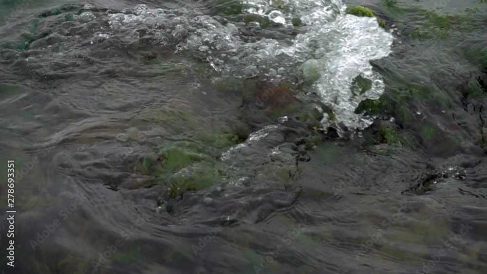 Slow motion sea wave washes the stones covered with green algae on the coast Slow motion sea wave washes the stones covered with green algae on the coast