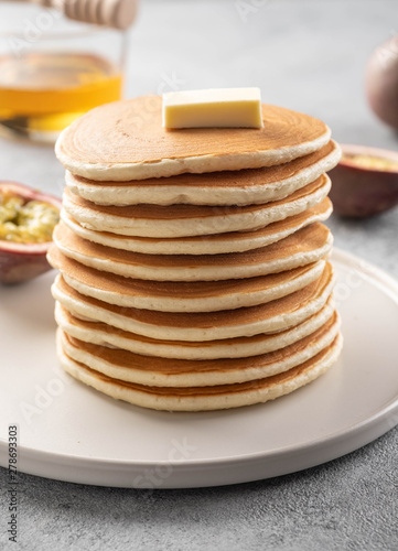 Pancakes stack with butter and honey. Grey backround.