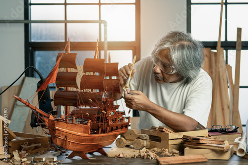 Fotografija asian senior carpenter concentrating to his woodwork in workshop as hobby
