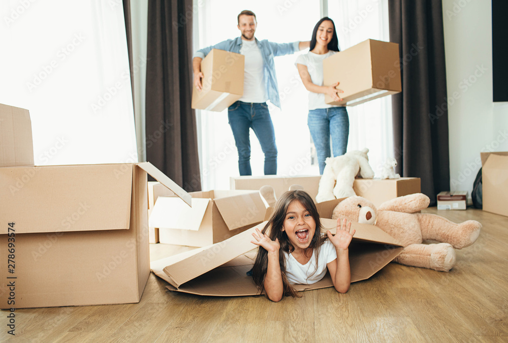 little girl playing with cardboard boxes. Daughter moving into new house with her parents little girl playing with cardboard boxes. Daughter moving into new house with her parents