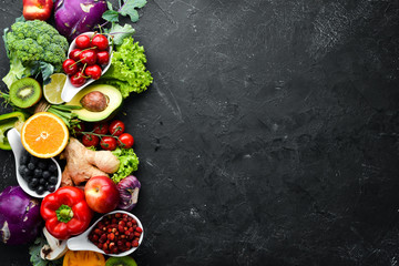 Fresh vegetables and fruits on a black background. Vitamins and minerals. Top view. Free space for your text.