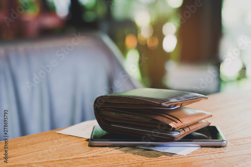 Soft tone of Money and credit card in a leather wallet on wooden table and bill slip background