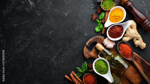 Colorful herbs and spices for cooking. Indian spices. On a black stone background. Top view.