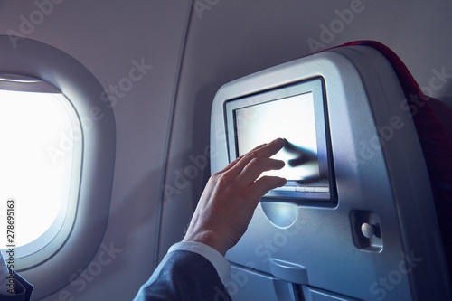 Man using touchscreen in modern airplane seat.