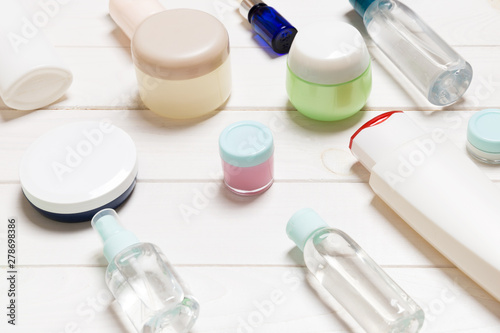 Close-up view of cosmetic bottles, jars, containers and sprays on white wooden background. Beauty concept with copy space