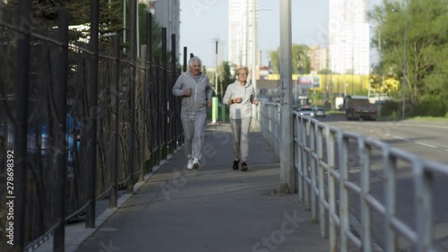 Wallpaper Mural Cheerful active senior man and woman jogging along sidewalk in city Torontodigital.ca