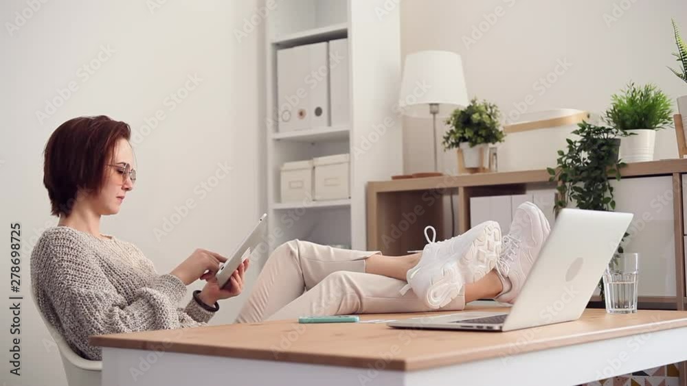Young woman plays on her tablet at her home office. She wins the game. Suddenly she receives the phone call from her client and starts working Young woman plays on her tablet at her home office. She wins the game. Suddenly she receives the phone call from her client and starts working