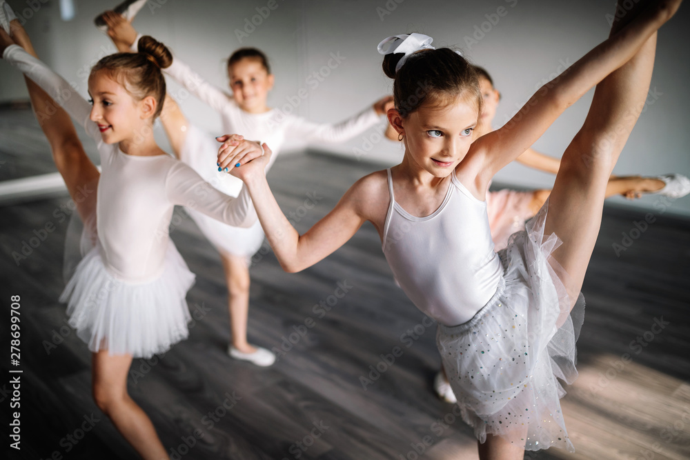 Naklejka premium Group of fit happy children exercising ballet in studio together