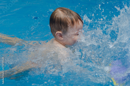 little boy swims in the pool and splashes