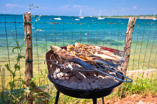 Fish on the grill by the mediterranean beach, idyllic vacation food preparing