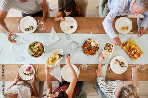 Konstfotografi Three generation white family sitting at a dinner table together serving a meal,
