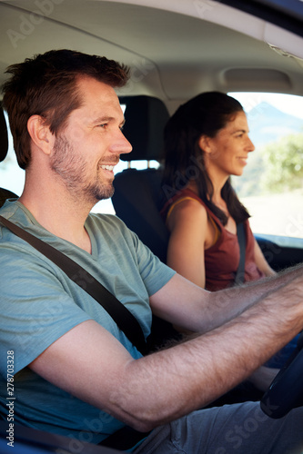 Smiling mid adult white couple driving in their car, close up, side view, vertical © Monkey Business