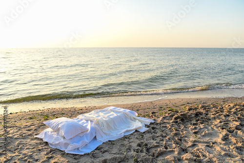 Bed with bed linen on the beach