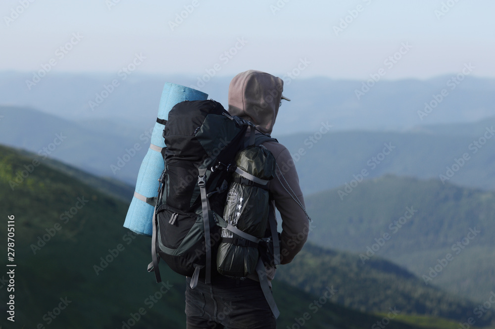 Male tourist on top of gray mountain in fog in summer.