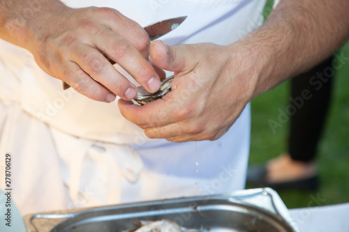 man shucking fresh oysters with a knife